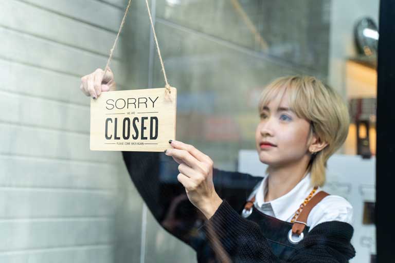 Lady putting closed up sign in window