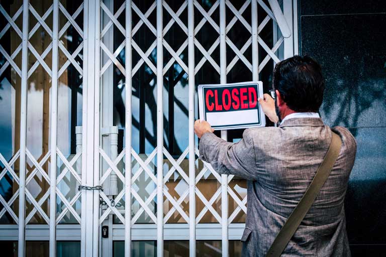 Male Business owner closing his business activity due economy crisis putting closed sign on the door