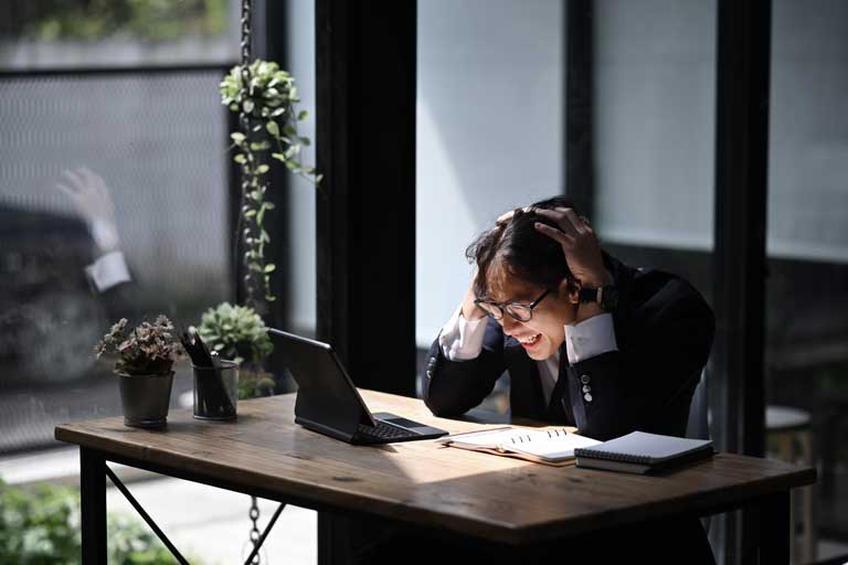 Frustrated businessman holding his head looking at a laptop