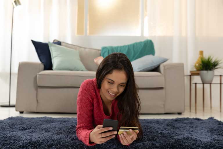 Young woman making a purchase through a smartphone in her living room